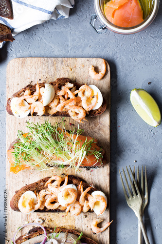 Open sandwiches with herring and onions, salmon, shrimps with rye bread, vertical, selective focus