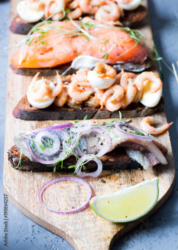 Open sandwiches with herring and onions, salmon, shrimps with rye bread, vertical, selective focus