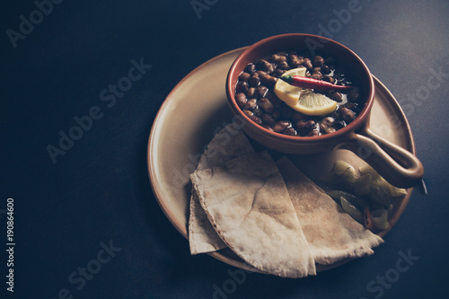 A full length color studio image of Egyptian, Arabian, Middle Eastern Traditional food (Fava Beans with Lemon and Chili Red Paprika) A.K.A (Foul) - Also served in Lebanon and most of Arabian countries