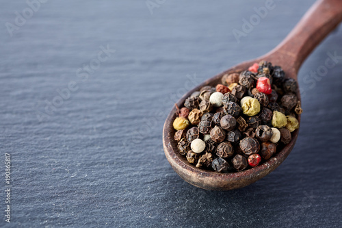Chinese pepper, Sichuan pepper in wooden spoon on black slate stone plate photo