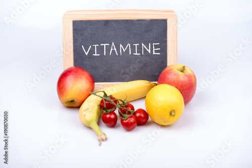 Obst und Gemüse mit einer Tafel auf der Vitamine steht