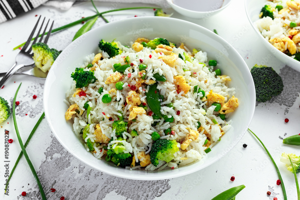 Fried rice with vegetables, broccoli, peas and eggs in a white bowl. soy sauce. healthy food Fried rice with vegetables, broccoli, peas and eggs in a white bowl. soy sauce. healthy food