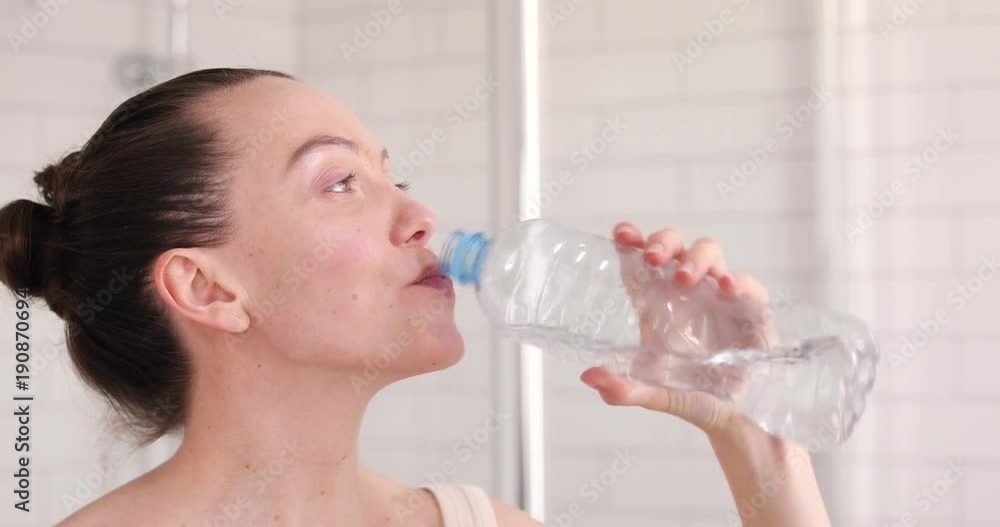 Young woman drinking mineral water bottle at home Young woman drinking mineral water bottle at home