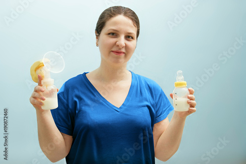 smiling nurse is holding breast pump, bottle of milk. mixed feeding, preserving lactation of working mom. Help with breastfeeding, problems sucking, seizing nipple, lack of milk. Natural motherhood.