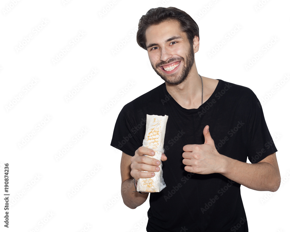 A young handsome man, an Arab, eats with pleasure Donner kebab Shaurma and shows a super sign. Isolation background A young handsome man, an Arab, eats with pleasure Donner kebab Shaurma and shows a super sign. Isolation background