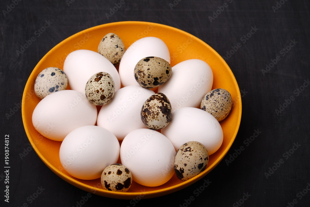 Fresh chicken and quail eggs on yellow plate. Top view. Healthy food and organic farming concept Fresh chicken and quail eggs on yellow plate. Top view. Healthy food and organic farming concept