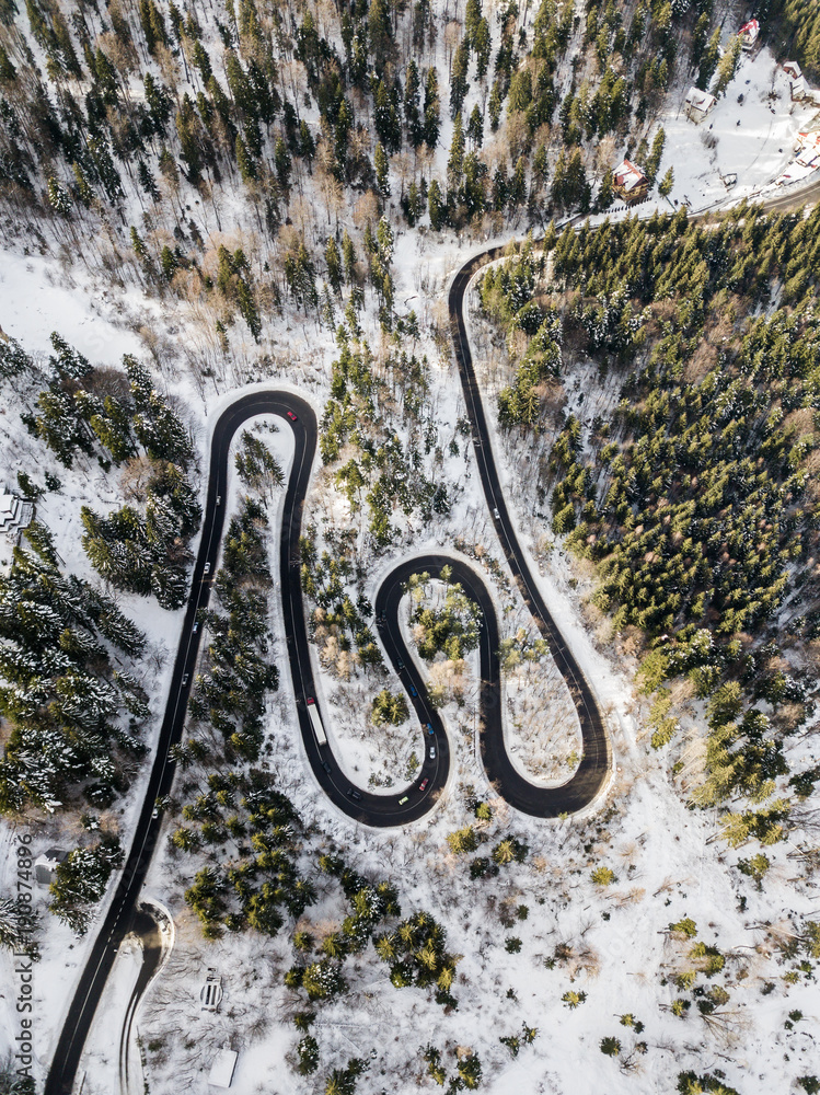 Winding road from high mountain pass, in winter time. Aerial view by drone . Romania	