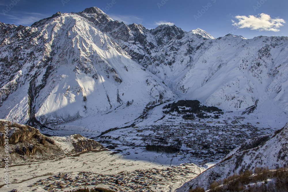 Obraz premium Stepantsminda (Kazbegi) and Gergetti are two settlements located in the highland part of Georgia, near the border with Russia. Winter landscape, top view.