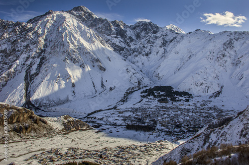 Stepantsminda (Kazbegi) and Gergetti are two settlements located in the highland part of Georgia, near the border with Russia. Winter landscape, top view. photo