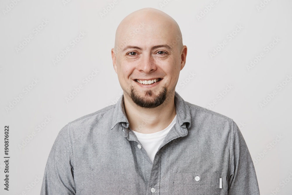Close-up portrait of happy bald european with beard expressing confidence and reassurance, standing over gray background. Mature man started business with his old friend, feeling it will be successful Close-up portrait of happy bald european with beard expressing confidence and reassurance, standing over gray background. Mature man started business with his old friend, feeling it will be successful