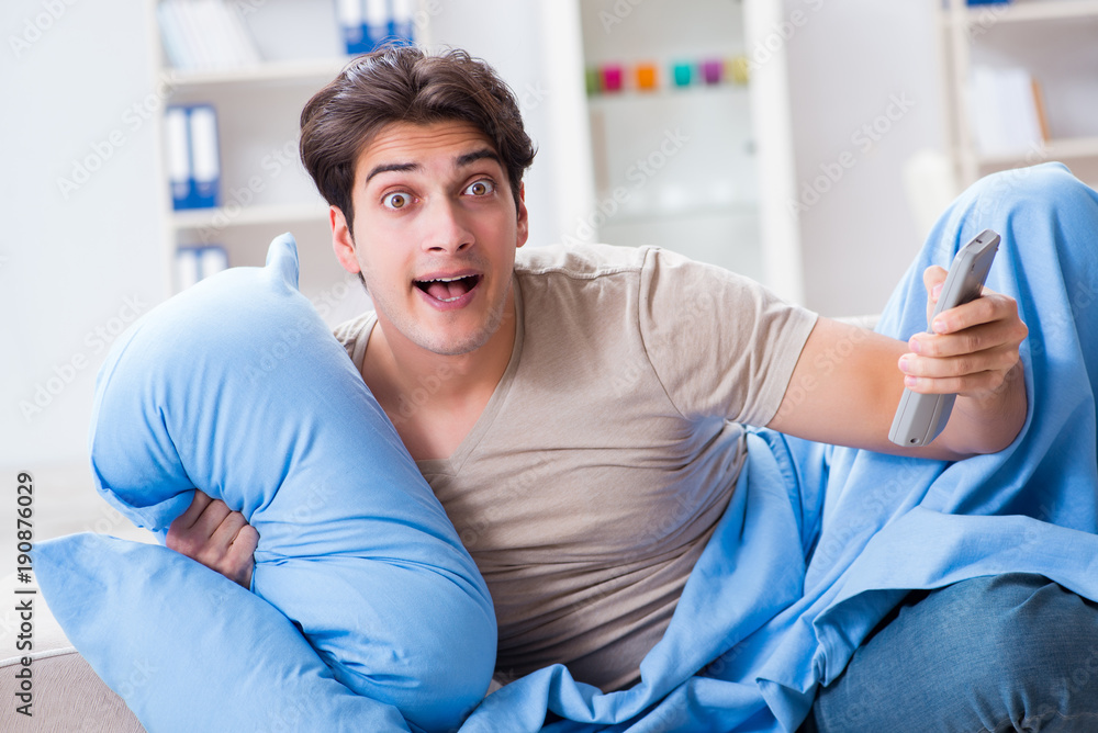 Fototapeta premium Man watching tv from bed holding remote control unit