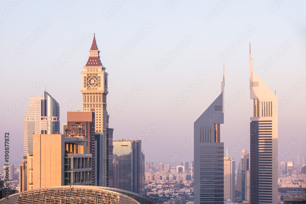 The skyline of Dubai DIFC district during a colorful sunset as viewed from a rooftop. Dubai, UAE. The skyline of Dubai DIFC district during a colorful sunset as viewed from a rooftop. Dubai, UAE.