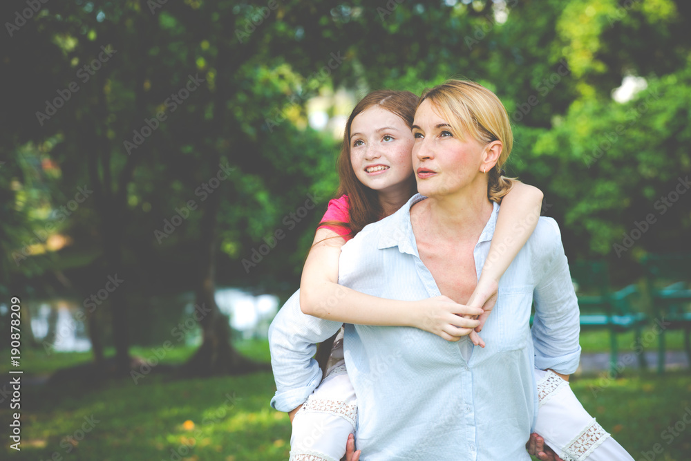 Small happy girl enjoying a piggyback ride on her mothers back Small happy girl enjoying a piggyback ride on her mothers back