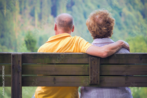 middle aged male and female sitting on bench, engaged people looking the nature view