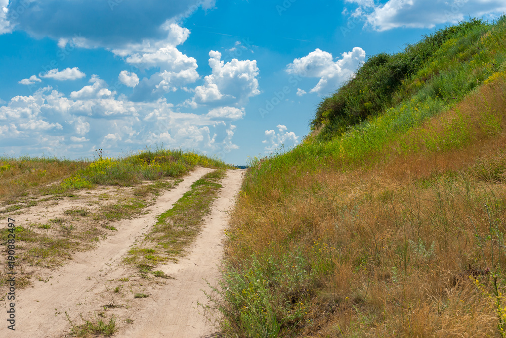 Sandy country road leading on a hill at summer season in Ukraine