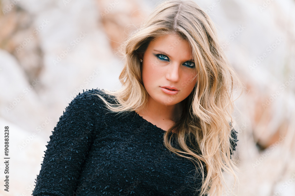 Portrait of Fashionable young woman in black dress posing in, rocky background in the forest. Portrait of Fashionable young woman in black dress posing in, rocky background in the forest.