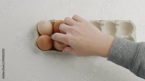 woman's hand open an eggbox with brown eggs ant take off oneof them photo