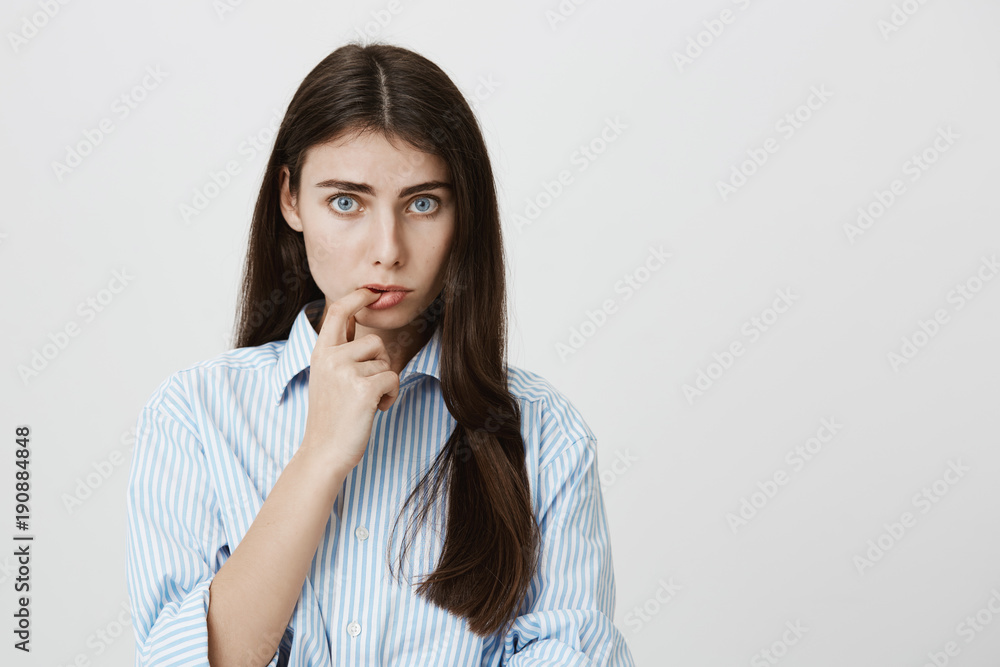 Portrait of attractive adult european woman making innocent look, biting finger and looking uncertain at camera, over gray background. Dear, I really do not know where is your credit card Portrait of attractive adult european woman making innocent look, biting finger and looking uncertain at camera, over gray background. Dear, I really do not know where is your credit card