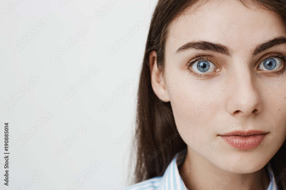 Close-up side portrait of gentle pretty european student looking at camera while standing against gray background. Woman with magnificent blue eyes waits till her boyfriend take photo of her Close-up side portrait of gentle pretty european student looking at camera while standing against gray background. Woman with magnificent blue eyes waits till her boyfriend take photo of her