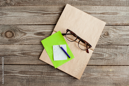 A craft notebook with a pencil and eyeglasses on wooden boards. photo