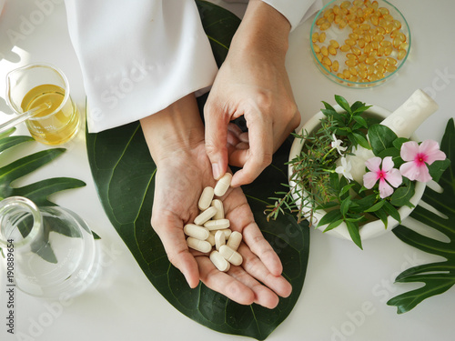 scientist or doctor making herbal medicine with herb leaves , capsule, tablets. hands.top view. photo