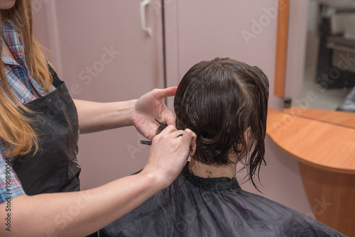A professional hairdresser cuts hair to a woman in a beauty salon. The process of creating a stylish hairstyle.