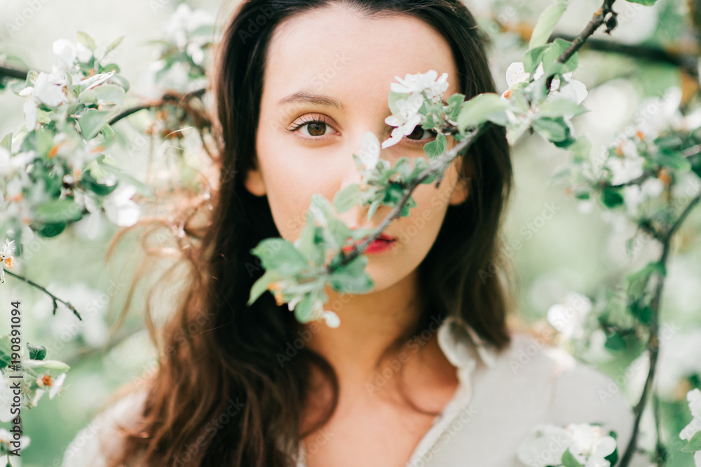 Spring apple trees in blossom. Tenderness, easiness and femininity. Young nice brunette girl enjoying flowers at beautiful nature. Cute happy teenager female relaxing outdoor in blooming garden. Spring apple trees in blossom. Tenderness, easiness and femininity. Young nice brunette girl enjoying flowers at beautiful nature. Cute happy teenager female relaxing outdoor in blooming garden.