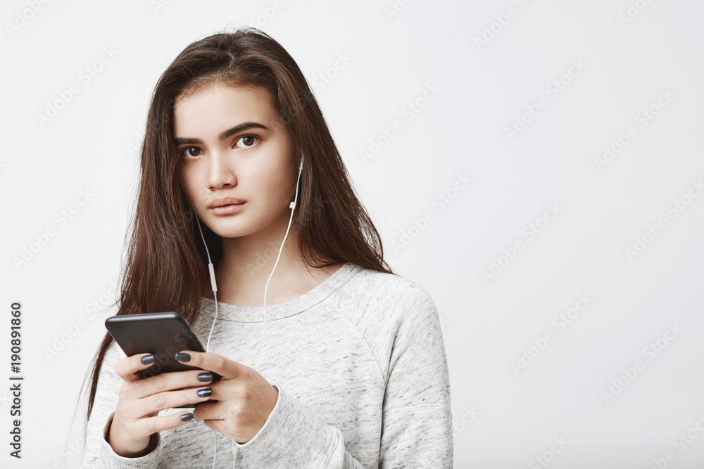 Portrait of cute attractive caucasian woman with long brown hair in trendy sweatshirt, listening to music and messaging with casual expression. Boy talks to her while she in headphones and can't hear Portrait of cute attractive caucasian woman with long brown hair in trendy sweatshirt, listening to music and messaging with casual expression. Boy talks to her while she in headphones and can't hear