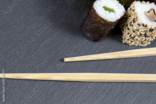 Sushi with chopsticks on black background