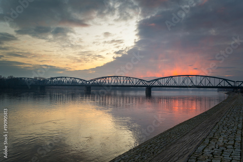 Zachód słońca w mieście Toruń , oświetla most na rzece Wiśle, Polska