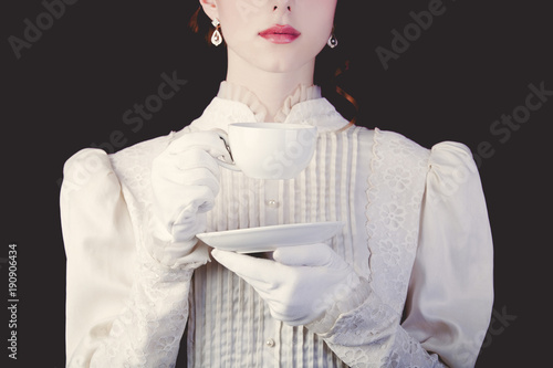 woman in white victorian era clothes with cup of tea