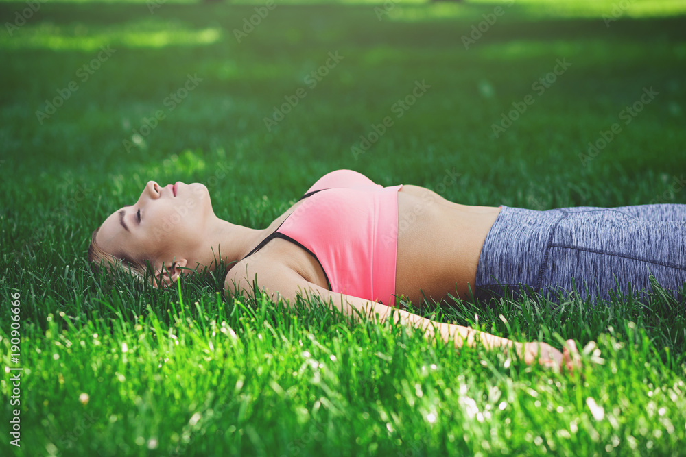 Exhausted woman after yoga training lying on the grass Exhausted woman after yoga training lying on the grass