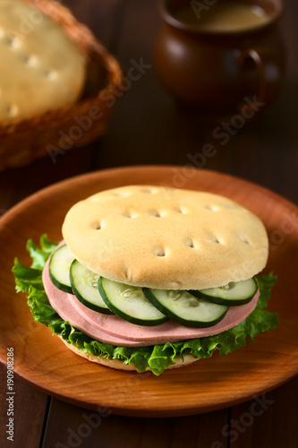 Traditional Chilean Hallulla bread roll sandwich with lettuce, cold cut and cucumber, photographed with natural light (Selective Focus on the front of the sandwich) photo