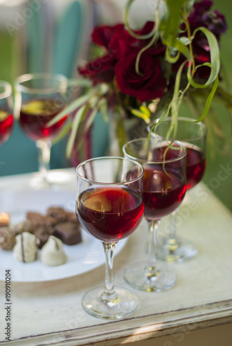 Chocolate truffles candys and glasses with red wine on white wooden table