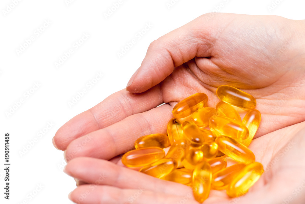 Yellow capsules in hands on a white background. Yellow capsules in hands on a white background.