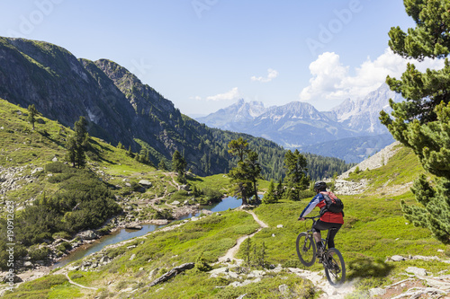 Mountainbiker downhill on Reiteralm with mountain Dachstein in Styria Austria
