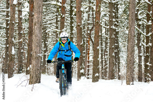 Cyclist in Blue Riding the Mountain Bike in Beautiful Winter Forest. Extreme Sport and Enduro Biking Concept.