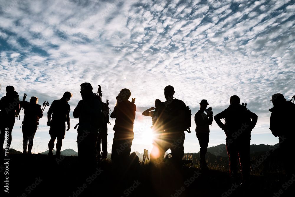 Sunrise in the Algau region of Germany- group of young adult hikers standing on a mountain during golden hour with dramatic sky Sunrise in the Algau region of Germany- group of young adult hikers standing on a mountain during golden hour with dramatic sky