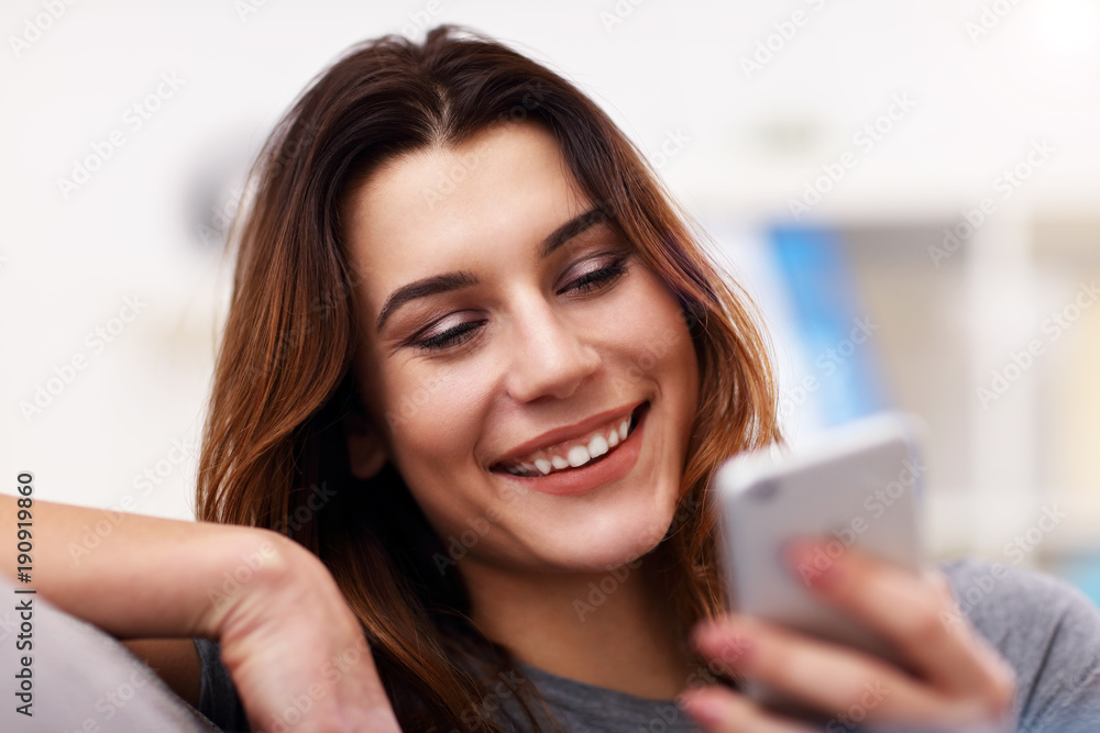 Happy adult woman using phone at home in the living room Happy adult woman using phone at home in the living room