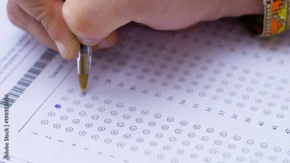Student's hand marking multiple choice test