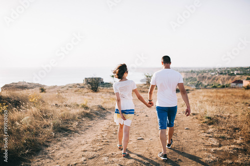 young loving couple walking with a beautiful view of the sea and mountains on sunset