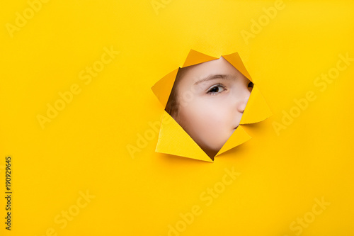 girl looking through a hole in colored paper © jyliagorbacheva