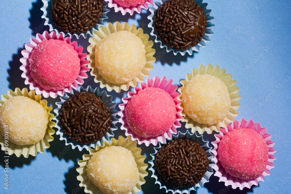 Brigadeiro Beijinho and Bicho de Pe: sweets from Brazil. Child birthday party. Overhead of candy ball on blue table. Brigadeiro Beijinho and Bicho de Pe: sweets from Brazil. Child birthday party. Overhead of candy ball on blue table.