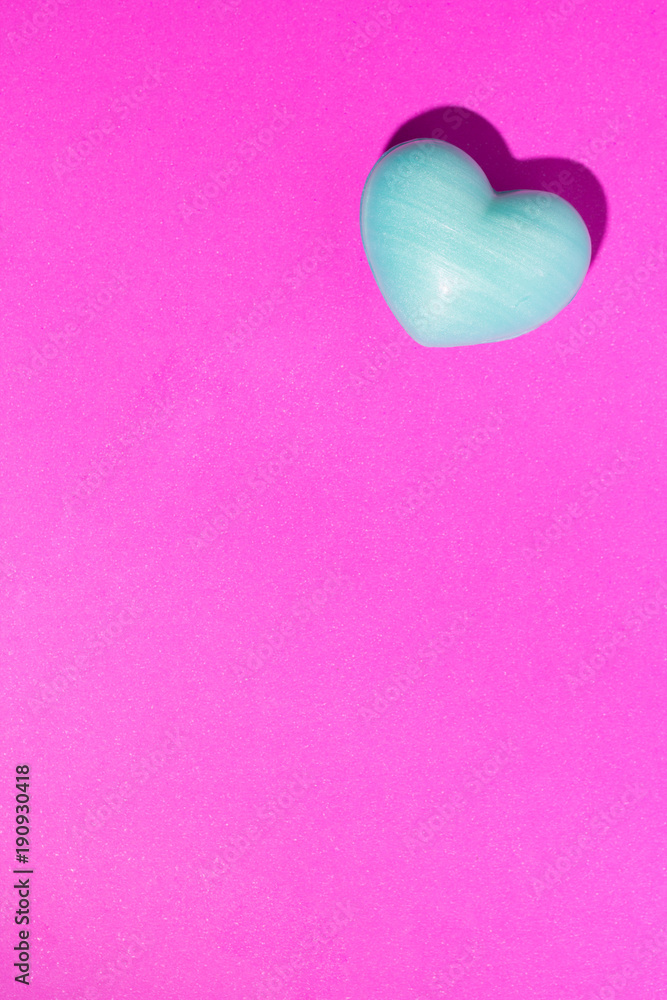 Turquoise heart shape over purple color table. Valentine Day concept.