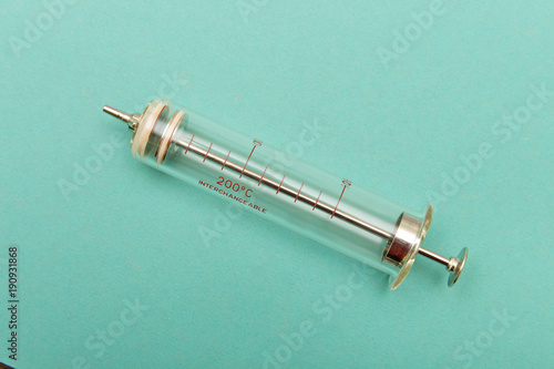 Reusable glass syringe on a turquoise background with copy space. Template