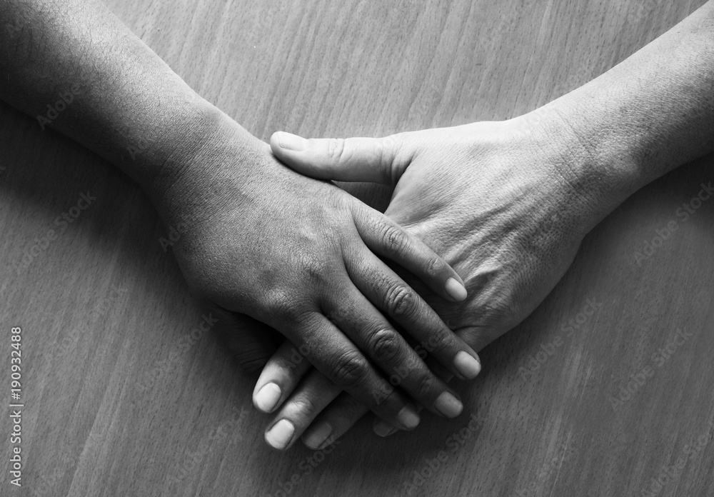 looking down on two hands and lower arms placed ontop of each other, the top hand is Asian and the bottom hand is caucasian looking down on two hands and lower arms placed ontop of each other, the top hand is Asian and the bottom hand is caucasian