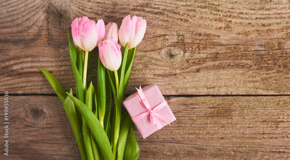 Valentines day background with pink tulips and gift box over wood board