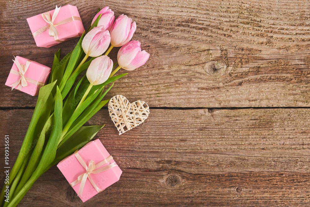 Valentines day background with pink tulips and gift box over wood board Valentines day background with pink tulips and gift box over wood board