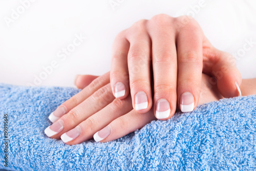 Woman hands with french manicure nails on blue towel