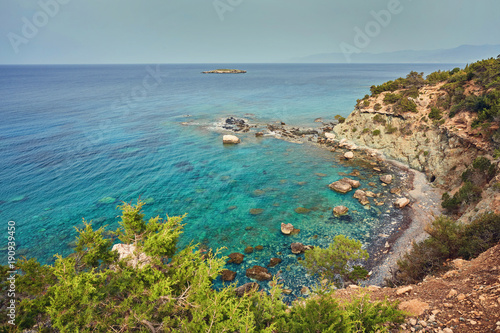 Stones and rocks in forefront with creamy surf ebbing and flowing on Polis beach, Cyprus.